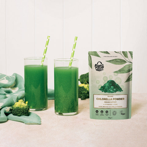 A package of Chlorella powder next to two glasses of green drink