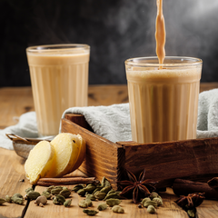 two glasses of Chai served in a tray with spices and ginger kept around the tray