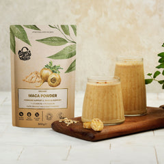 A package of Maca powder with two glasses of orange coloured drink served on a tray