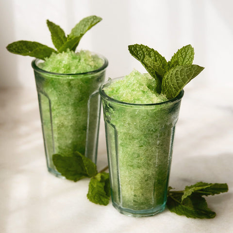 Two glasses of green slush with mint garnish