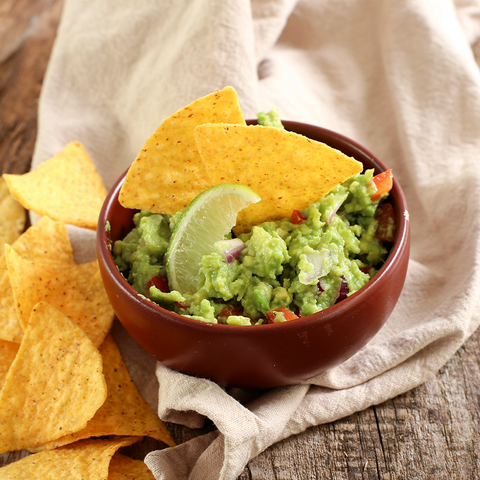 Guacamole in a bowl with nacho chips 